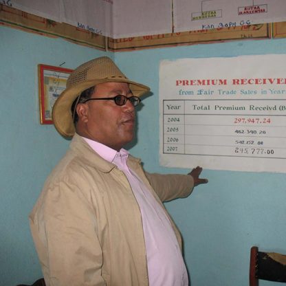 An Ethiopian coffee trader pointing to a tally of Fair Trade premiums received, which is painted on a wall