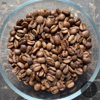 Close-up shot of Honduras La Peñita medium roasted coffee beans in a glass bowl.
