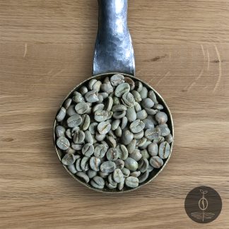 Close-up shot of Brazil Paubrazil green (raw) coffee beans in a handmade scoop with a wooden cutting board background.