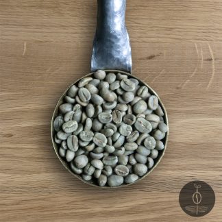 Close-up shot of Congo Kivu green (raw) coffee beans in a handmade scoop with a wooden cutting board background.