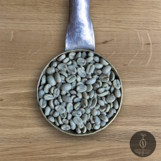 Close-up shot of Ethiopia Yirgacheffe green (raw) coffee beans in a handmade scoop with a wooden cutting board background.