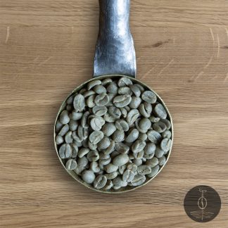 Close-up shot of Rwanda Kigayo green (raw) coffee beans in a handmade scoop with a wooden cutting board background.